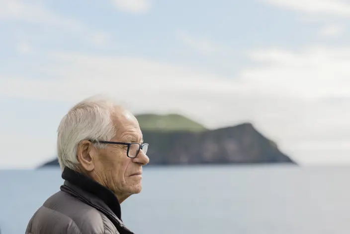 Eldri maður skoðar landslag við sjóinn
