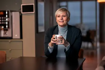 Woman with a coffee cup in an office dining area.