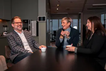 Þrennt fólk talar saman á kaffistofu á skrifstofu.